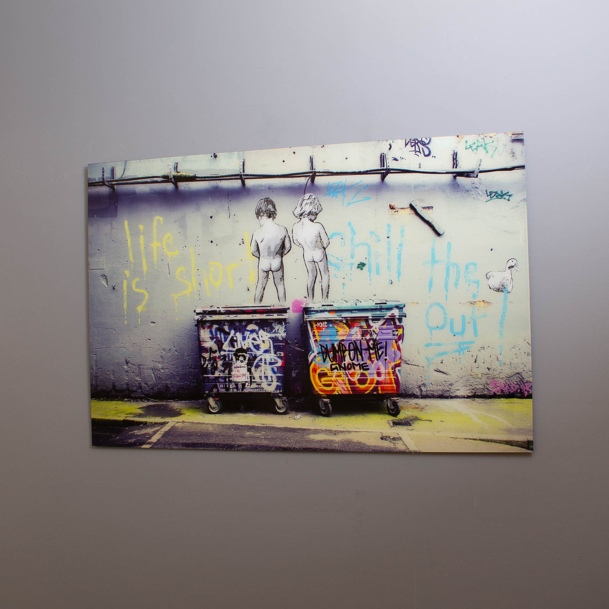 A piece of tempered glass wall art featuring a colorful graffiti print with text and vivid details, hung on a wall.